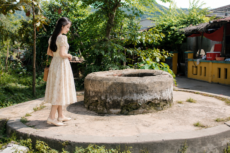 Diện đầm chữ A nhẹ nhàng tham quan giếng cổ Chăm cổ kính. (Ảnh được tạo bởi AI)